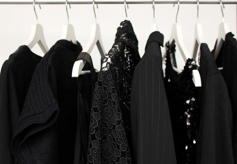 ein Reihe von schwarzen Kleidungsstücken auf weißen Kleiderbügeln