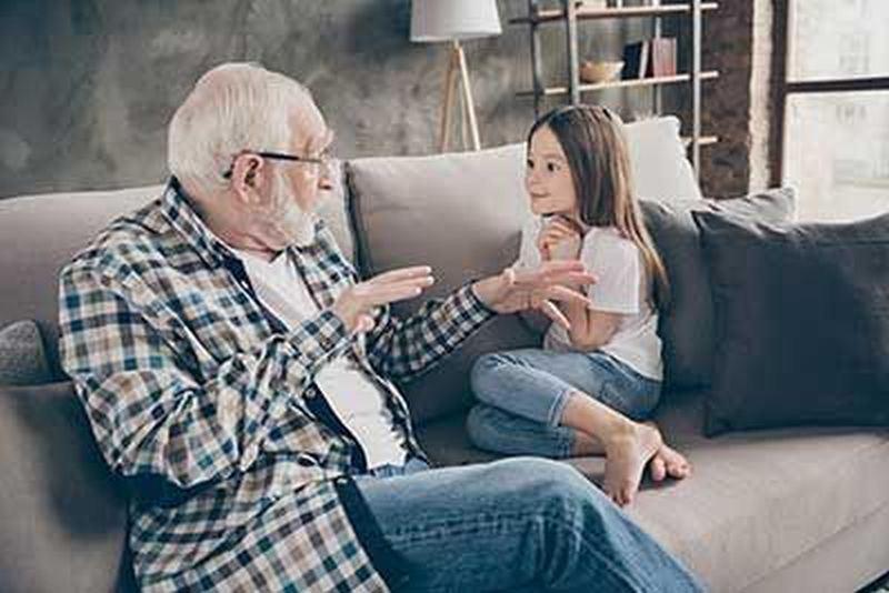 Opa redet mit seiner kleinen Nichte auf dem Sofa