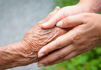 Zwei Junge Hände umhüllen eine alte-faltige Hand